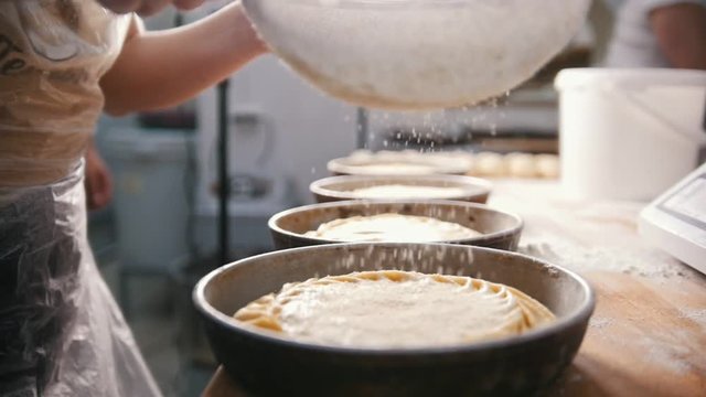 Cook sifts flour and sugar decorating baked products in the bakery