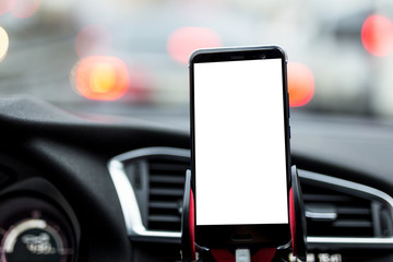 Smartphone or GPS device in a holder on car's dashboard with blurred traffic jam on the background. Mock up white emty screen for text