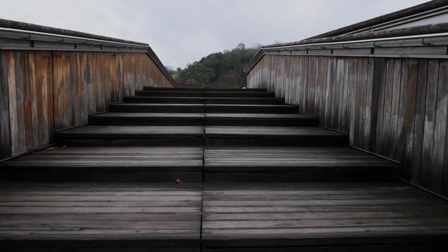 climbing wooden stairs that cross an urban river, bilbao