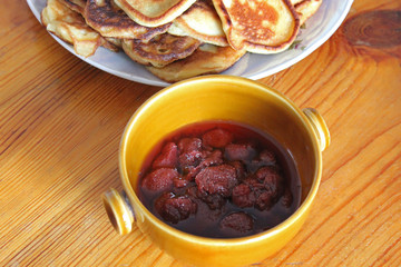 Pancakes and jam. Eating on a wooden table