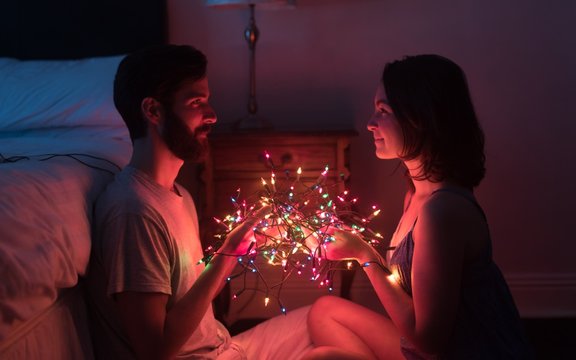 Romantic Couple Holding Fairy Lights In Dark Room