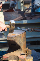 blacksmith performs the forging of hot glowing metal on the anvil