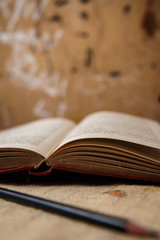 Ancient book and pencil in the foreground with abstract background