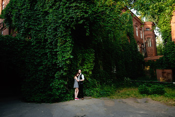 Fototapeta na wymiar Fashion lifestyle portrait of young perfect beautiful couple relaxed on their vacation, wearing casual clothes. Kissing and having fun together. They standing on the green wall
