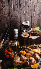 tasty grilled meat with vegetables and beer on wooden background