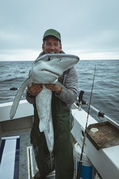 Happy fisherman holding shark fish