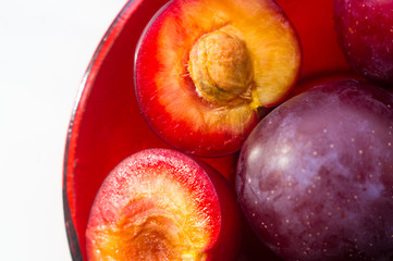 fresh plum fruit in the red saucer on white background