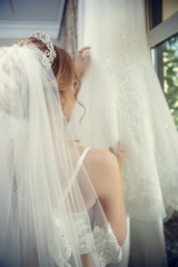 Gorgeous charming sexy bride in white lace dress in hotel room near the door of balcony