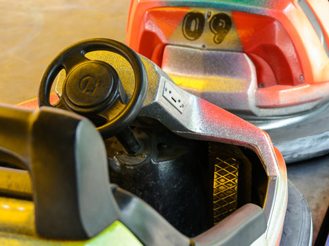 Close-up view of the cokpit of a colorful dodgem car, with steering wheel, pedal and coin slot in a funfair.