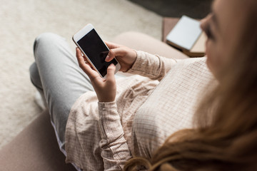 high angle view of young woman using smartphone on couch at home