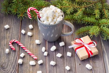 Hot coffee chocolate with marshmallow on rustic wooden table background, candy canes gift boxes fir tree
