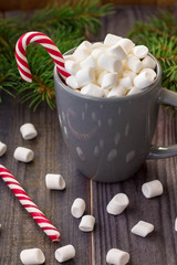 Obraz na płótnie Canvas Hot coffee chocolate with marshmallow on rustic wooden table background, candy canes gift boxes fir tree