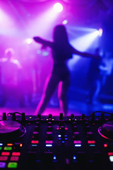 night club with DJ mixer and blurred silhouette of female dancer with a colorful background