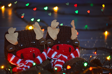 Christmas elk or moose socks with garland lights on gray wooden background. Merry Christmas, heart bokeh