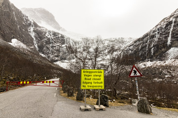 Trollstigen road is closed for the winter. A yellow sign stating the road is closed. Troll warning...