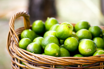Close up green organic limes in basket weave at market