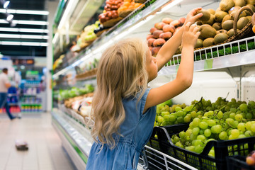 adorable female child choosing fruits in supermarket