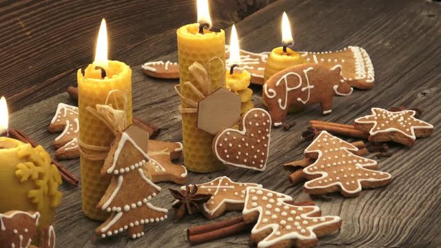 Christmas homemade gingerbread cookies on wooden desk. Yellow scented candles made from natural beeswax.