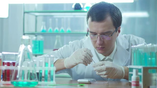 The lab technician looks into a flask with blue liquid in the laboratory