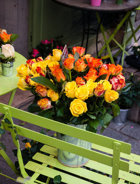 Florist shop. Yellow and orange roses bouquet with price tag in metal bucket on the green chair. Paris (France)