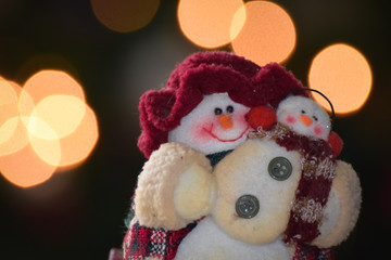 Cute snowman doll mother and child with blurry bokeh light background