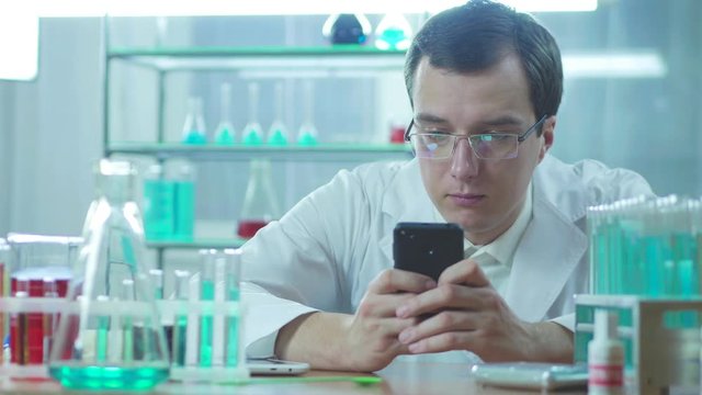 Doctor looks at mobile phone and working in laboratory. 
