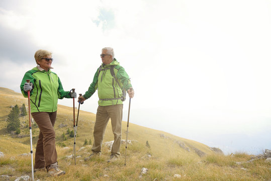 Senior tourist couple hiking at the beautiful mountains