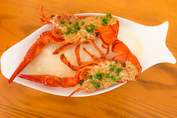 Top view of a red baked lobster with herbs on a white plate