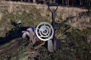 Metal detector and shovel in the forest

