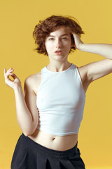 Beautiful and emotional girl on a yellow background without make-up and with natural skin