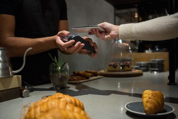 Woman paying bill through smartphone using NFC technology