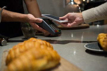 Obraz na płótnie Canvas Woman paying bill through smartphone using NFC technology