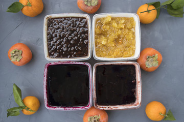 Four different types of jam on a gray background.