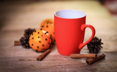 red Christmas mug ,cinnamon sticks and oranges on wooden backgr