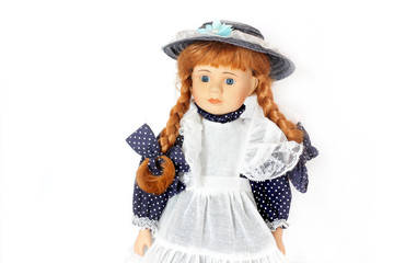 An old doll in a hat. Beautiful porcelain doll in a dress on a white background.