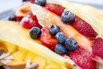 Multi berry crape and banana with chocolate sauce close up.