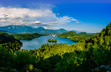 Colorful summer scene on the Bled lake with the famous Pilgrimage Church of the Assumption of Maria and Bled Castle and Julian Alps at background
