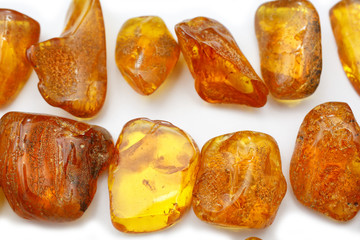 Amber. A lot of different transparent pieces of amber small and large on a white background. Red yellow pieces of amber with insects inside. Mineral for jewelers.  Natural stone. Fashion Decoration