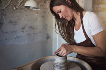 Female artisan creatively sculpting clay in her pottery studio