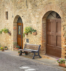 Fototapeta na wymiar alone bench before old door in Tuscany city in Italy