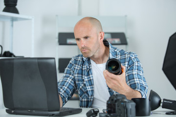 Naklejka na ściany i meble man holding camera while sitting at his working place