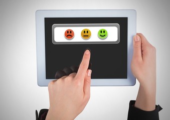 Hand holding tablet with smiley face feedback satisfaction