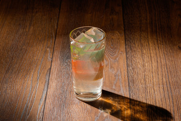 glass of water with ice on wood background.