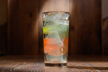 glass of water with ice on wood background.