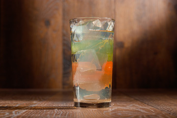 glass of water with ice on wood background.