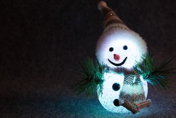 Fototapeta premium Funny snowman with friendly face lit in front of black background