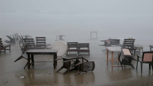 Rain and strong wind during sea storm blowing tables and chairs on beach cafe