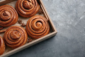 Wooden tray with sweet cinnamon rolls on table