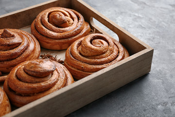 Wooden tray with sweet cinnamon rolls on table