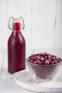 Cranberry juice in a bottle and a cranberries in a glass bowl
